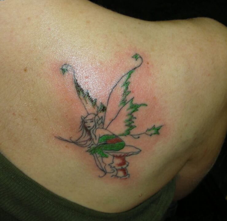 Beautiful Green And Red Color Ink Angel Sitting Tattoo On ...